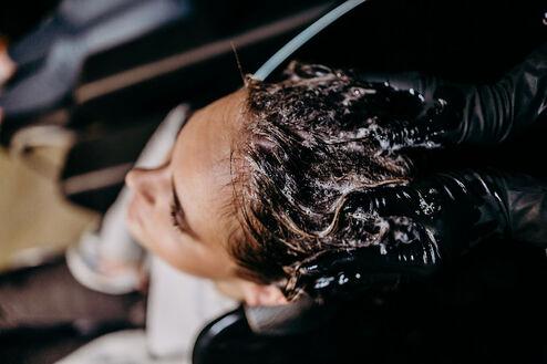 Dunkle lockige Haare bei einer Haarwäsche beim Friseur