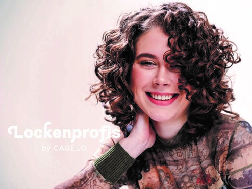 L&auml;chelnde Frau mit dunklen, lockigem Haarschnitt und Aufschrift "Lockenprofis"