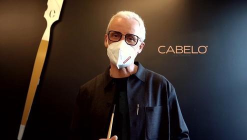 Ein Friseur in Münster präsentiert den Calligraphy Cut und trägt dabei eine Schutzmaske vor dem „Cabelo“ Logo.